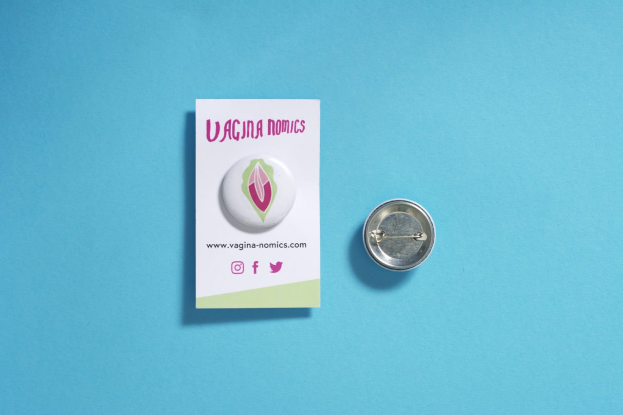 Front and back of a pin with the logo of the Vagina-nomics on it.