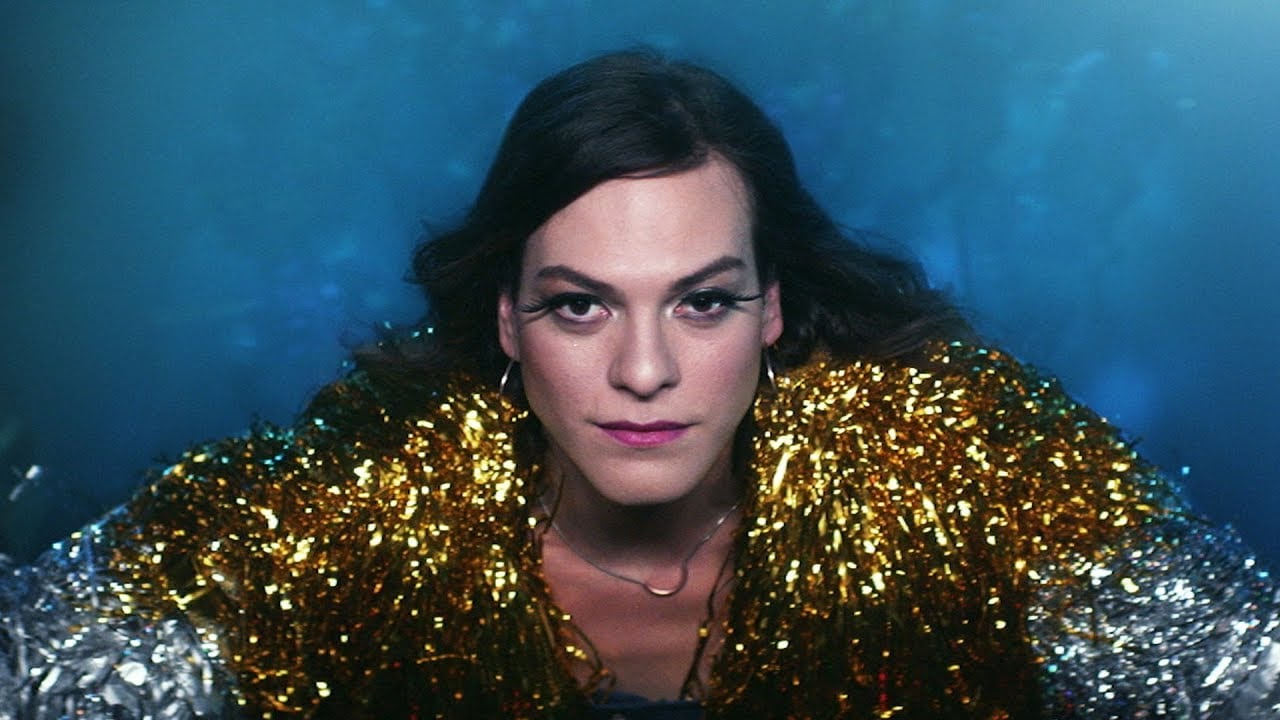 image of a woman looking out of the frame in a gold jacket, taken from the film A Fantastic Woman